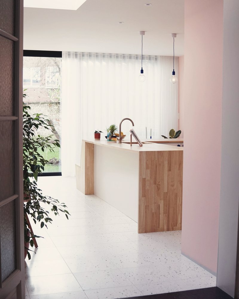 Narrow side-return kitchen with a long timber island and a rooflight running the depth of the room