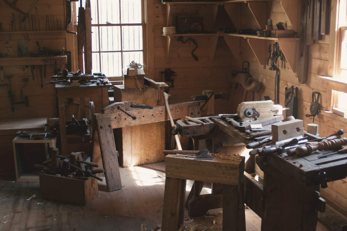 The joinery workshop at the yard with workbenches, clamps and hand tools under a tall window