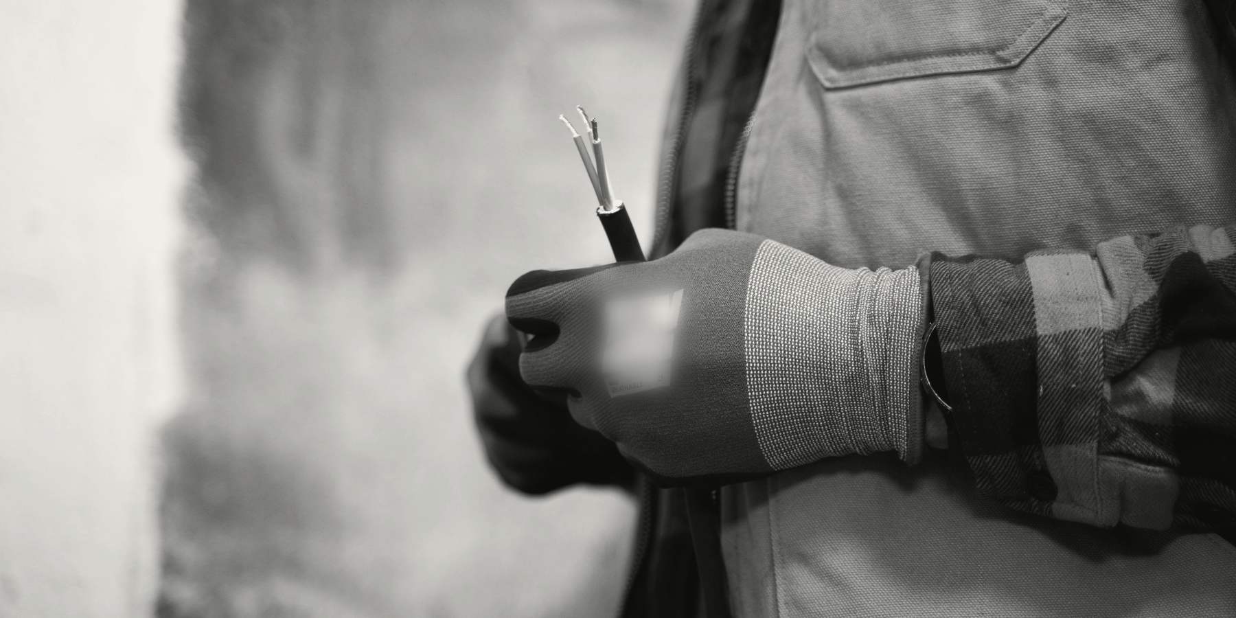 A gloved hand holding a stripped cable ready for connection
