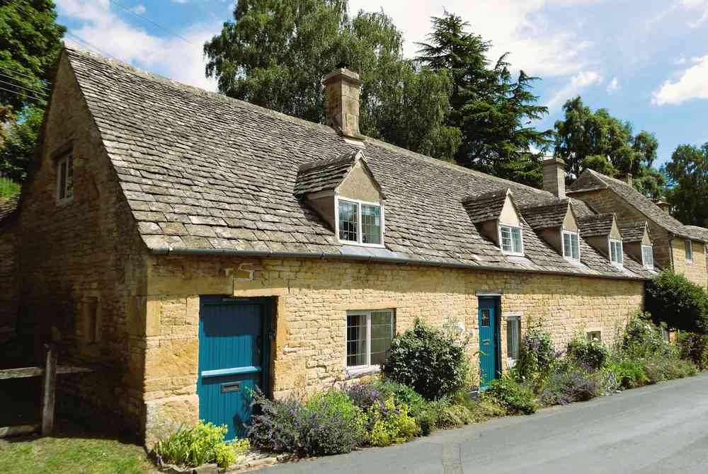 A row of honey-stone cottages with a blue door on a village street