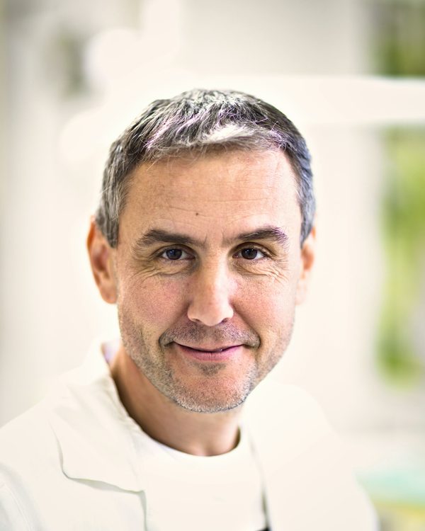 Dr Tom Pryce smiling, in a white coat